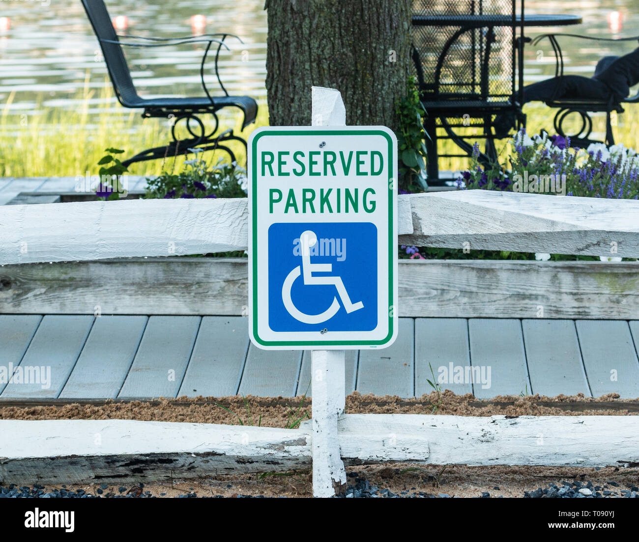 A reserved parking for handicapped sign is placed close to the water for the benefit of the person at a local beach with water in the background. Stock Photo
