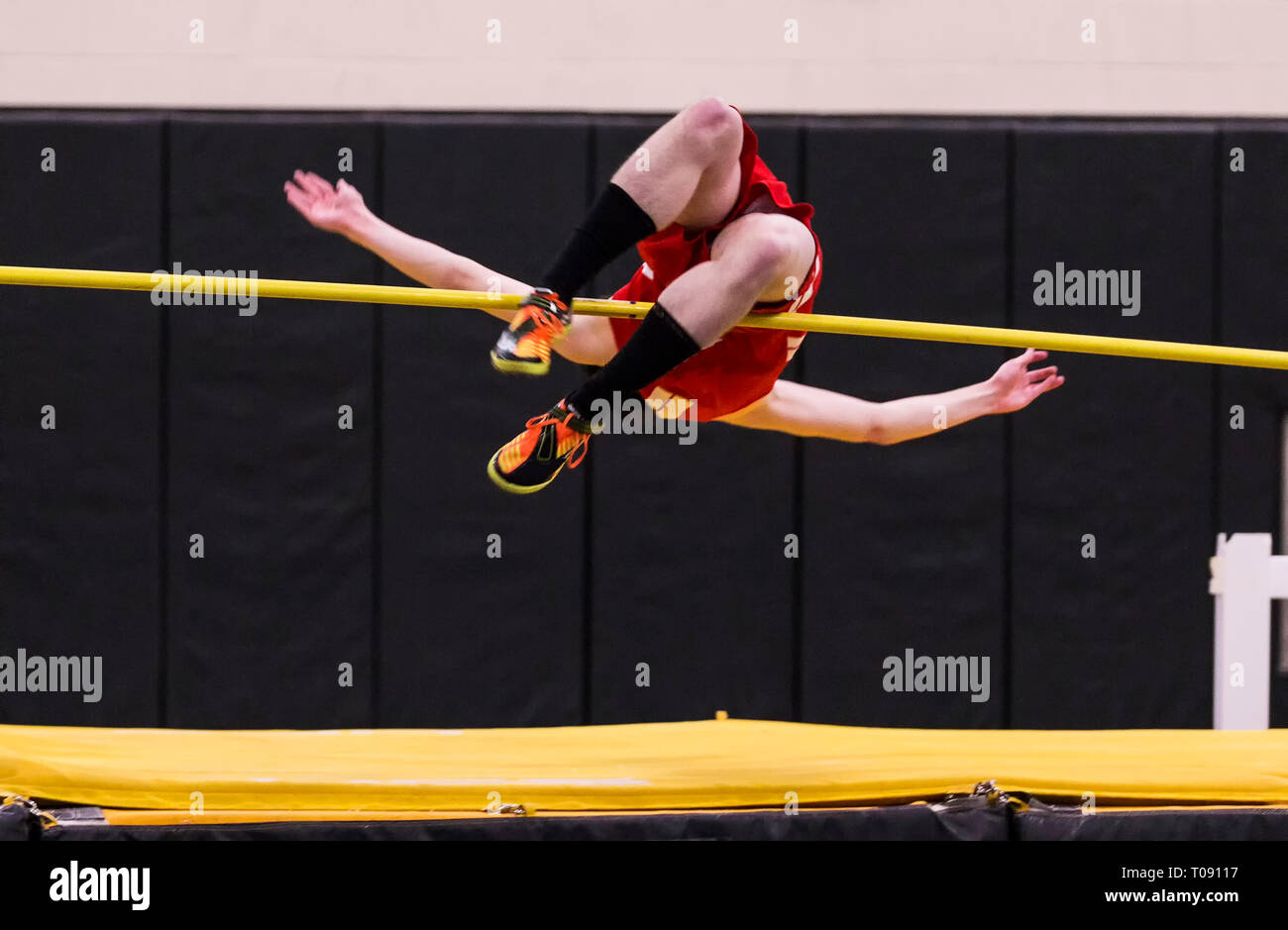 A high school high jumper competing in a track and field event attempting to clear the bar. Stock Photo