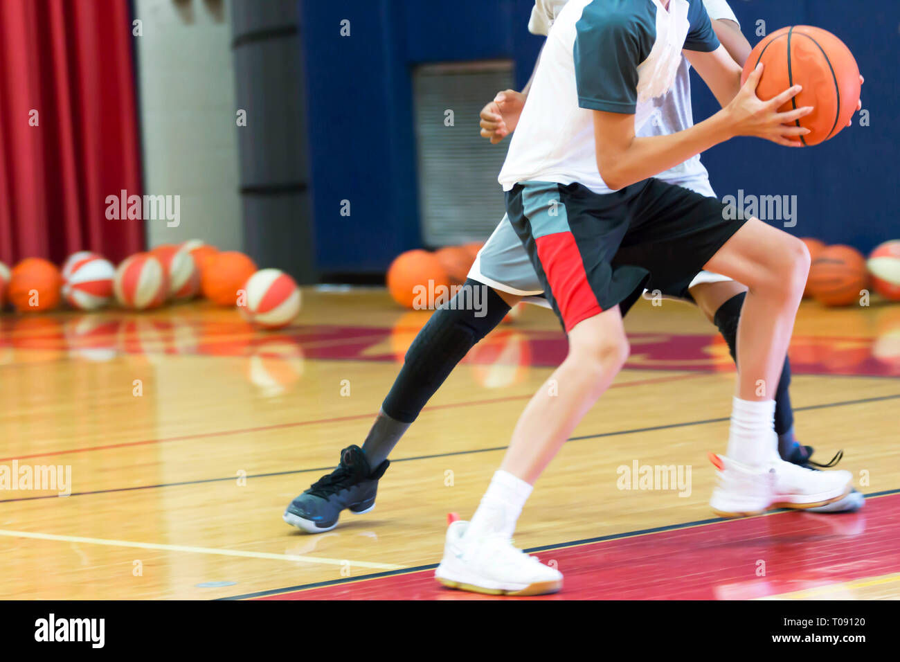 Two teenage male basketball players doing a one on one drill indoors at