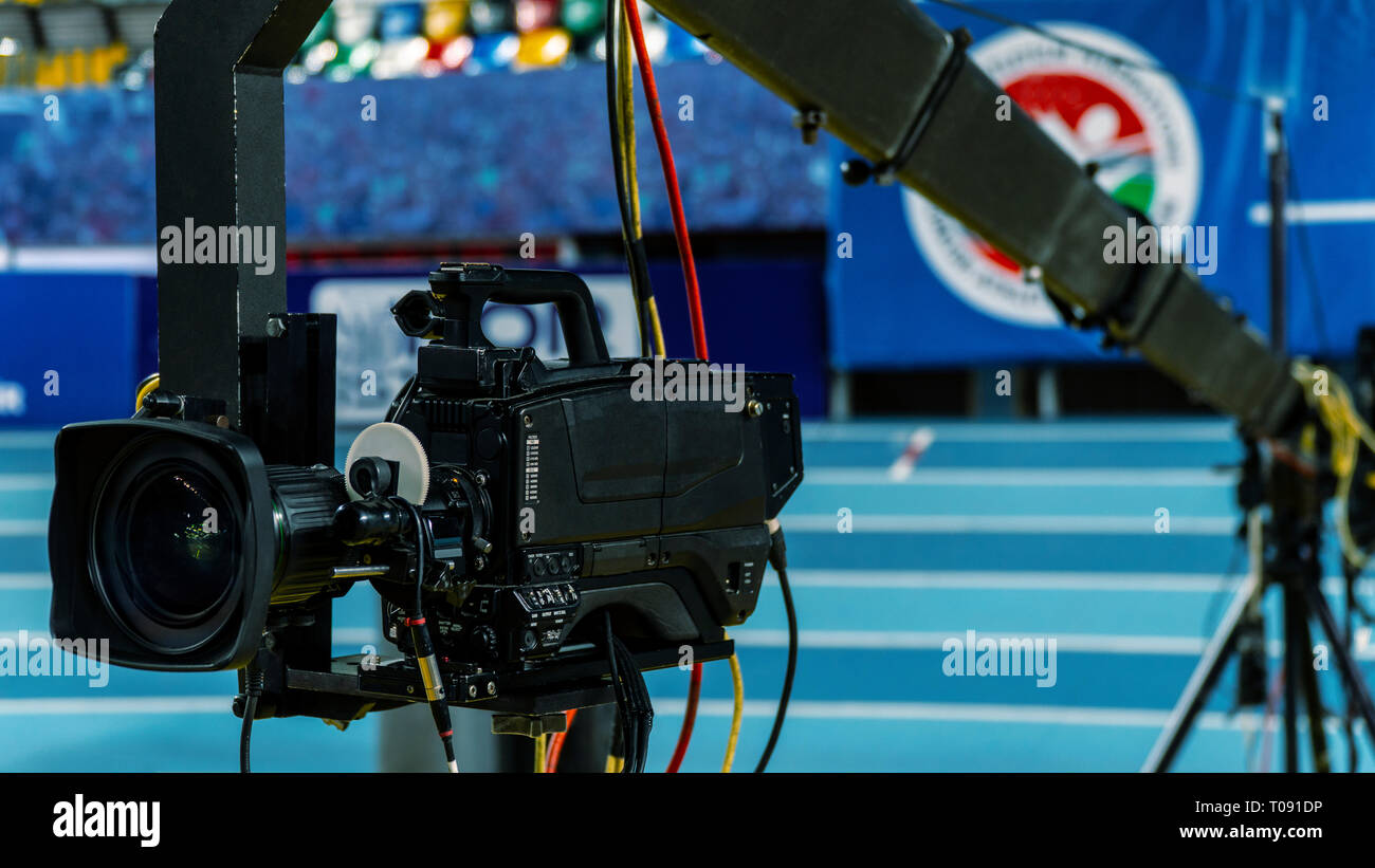 A television camera on a crane outside the studio. The video camera hanging on the crane prepares for a live sporting event. The live broadcast is ver Stock Photo