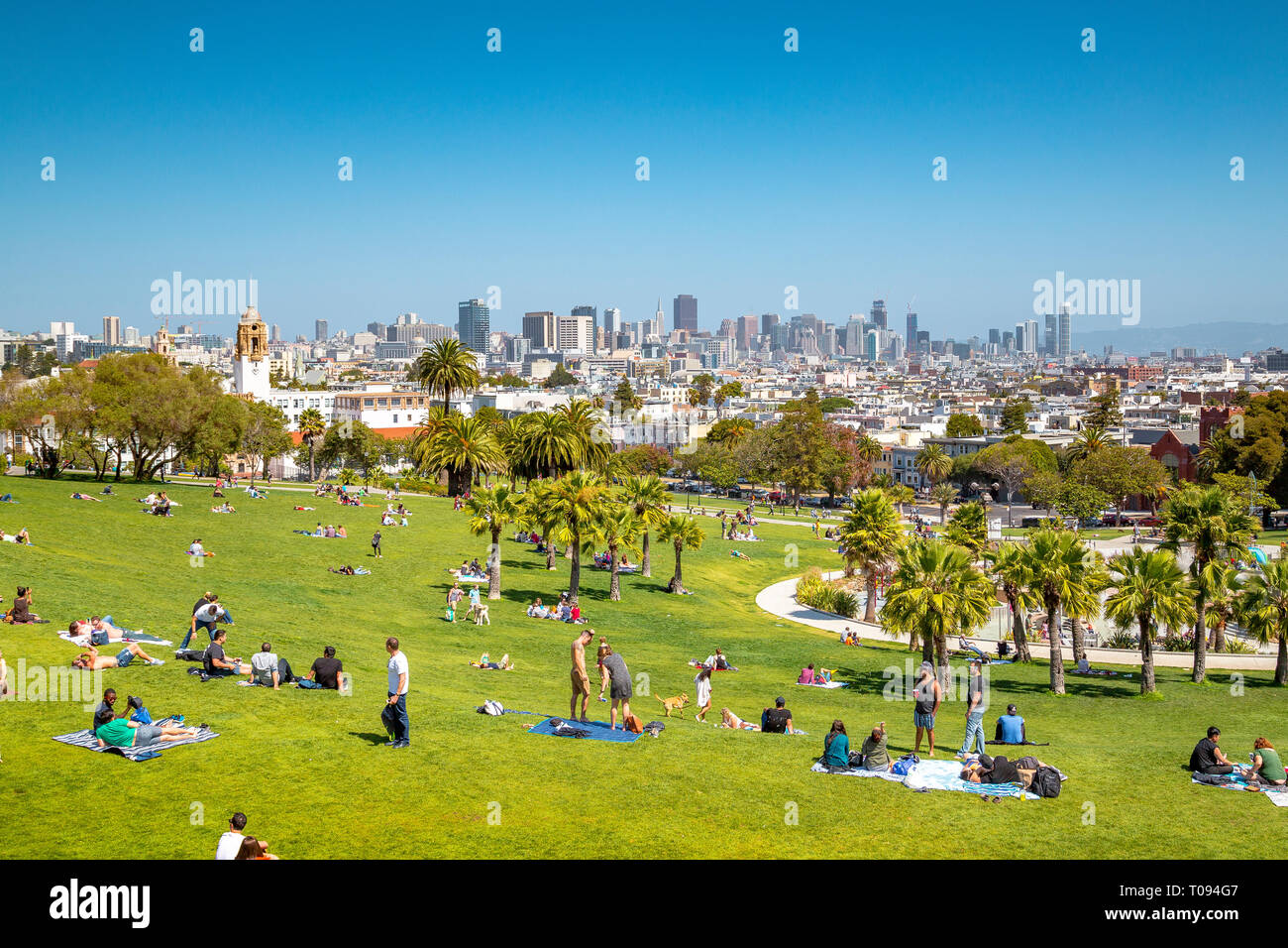 Panorama view of people enjoying the sunny weather on a beautiful day with clear blue skies with the skyline of San Francisco in the background, USA Stock Photo