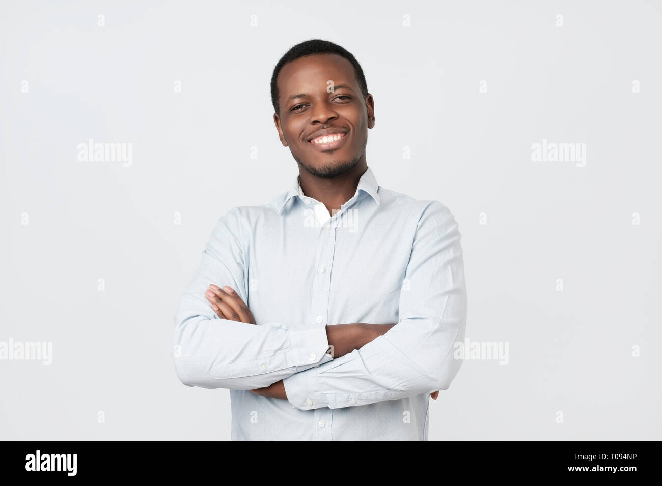 Laughing handsome young african man in shirt smiling confident Stock Photo