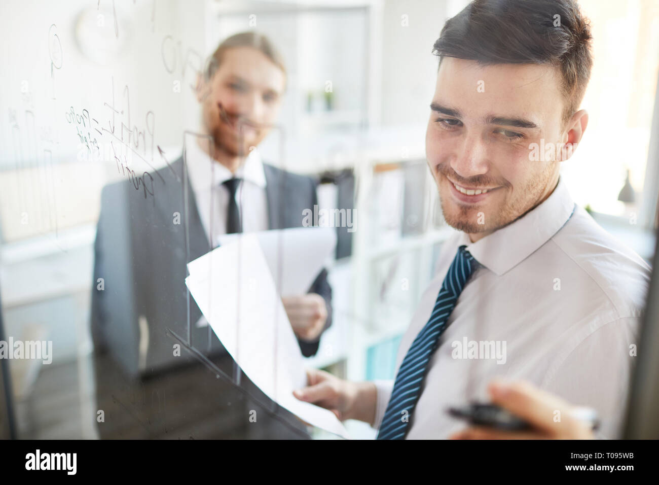 Analyst pointing at data on board Stock Photo