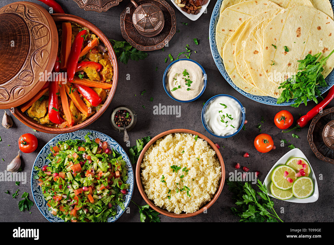 Moroccan food. Traditional tajine dishes, couscous and fresh salad on rustic wooden table. Tagine chicken meat and vegetables. Arabian cuisine. Top Stock Photo