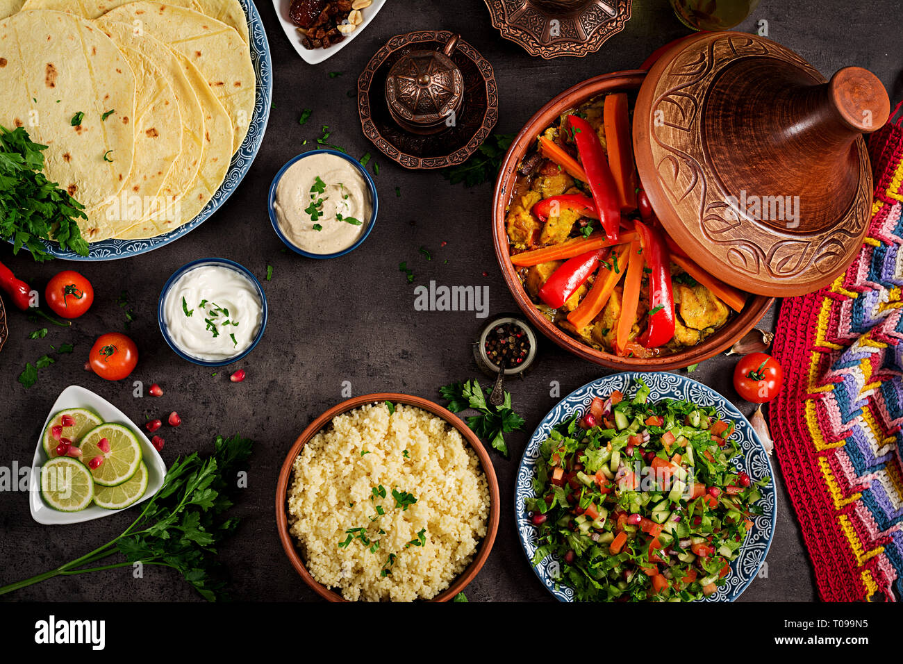 Moroccan food. Traditional tajine dishes, couscous and fresh salad on rustic wooden table. Tagine chicken meat and vegetables. Arabian cuisine. Top Stock Photo