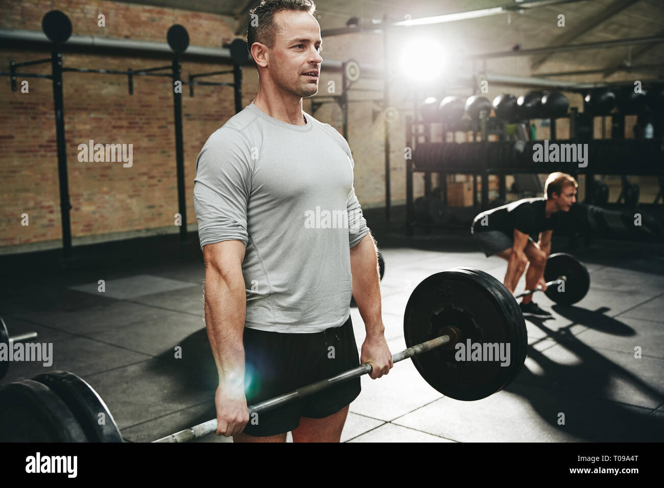 Fit man in sportswear preparing to lift a barbell with hearvy weights during a workout session at the gym Stock Photo