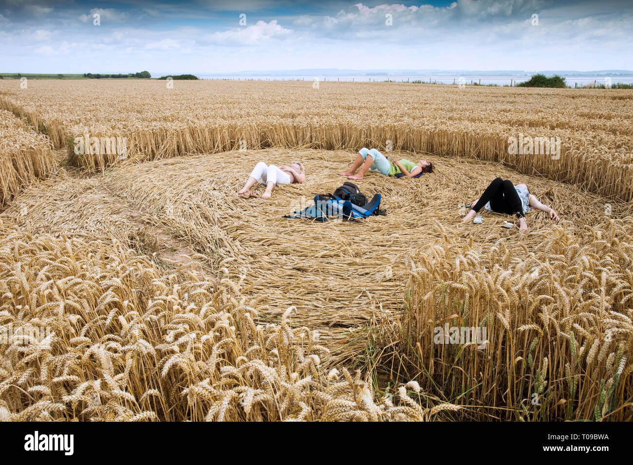 Great Britain, England, Gloucestershire.  Girls relaxing in a crop circle formation on the Severn Estuary, July 2010. Stock Photo