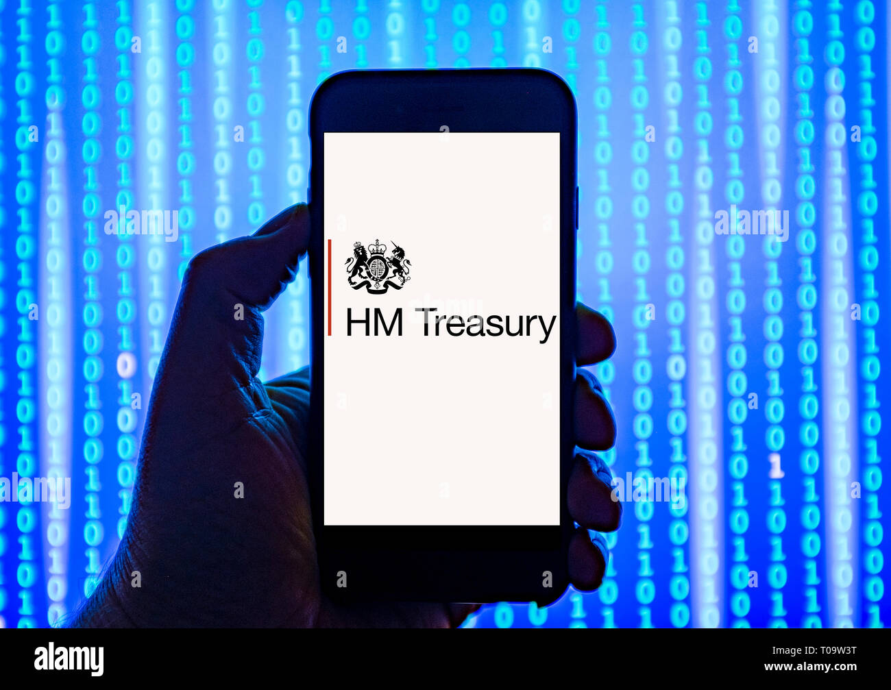 Person holding smart phone with   HM Treasury  logo displayed on the screen. Stock Photo