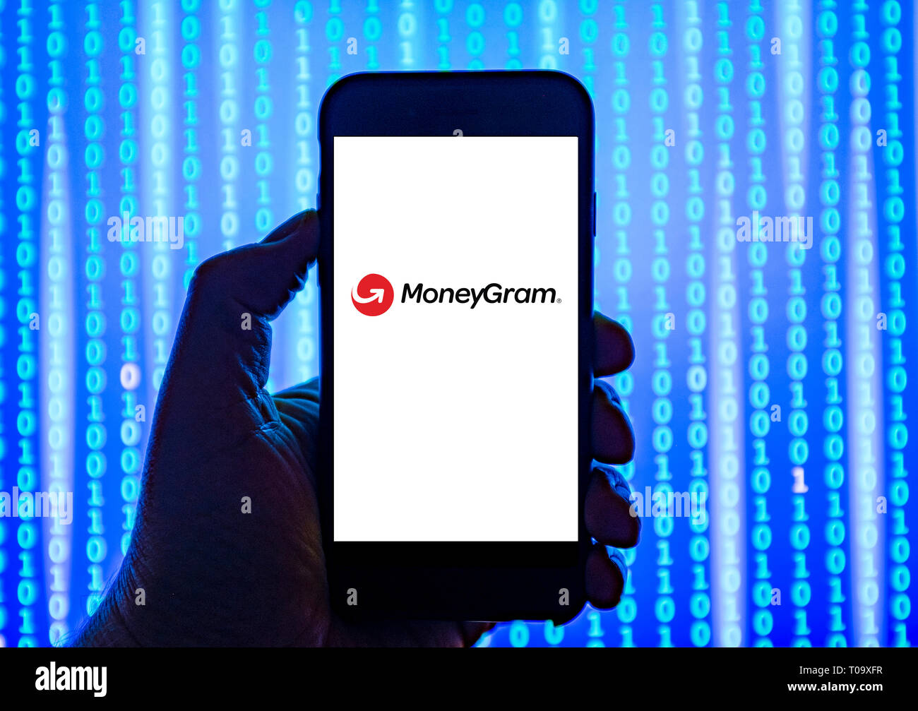 Person holding smart phone with Moneygram   logo displayed on the screen. Stock Photo