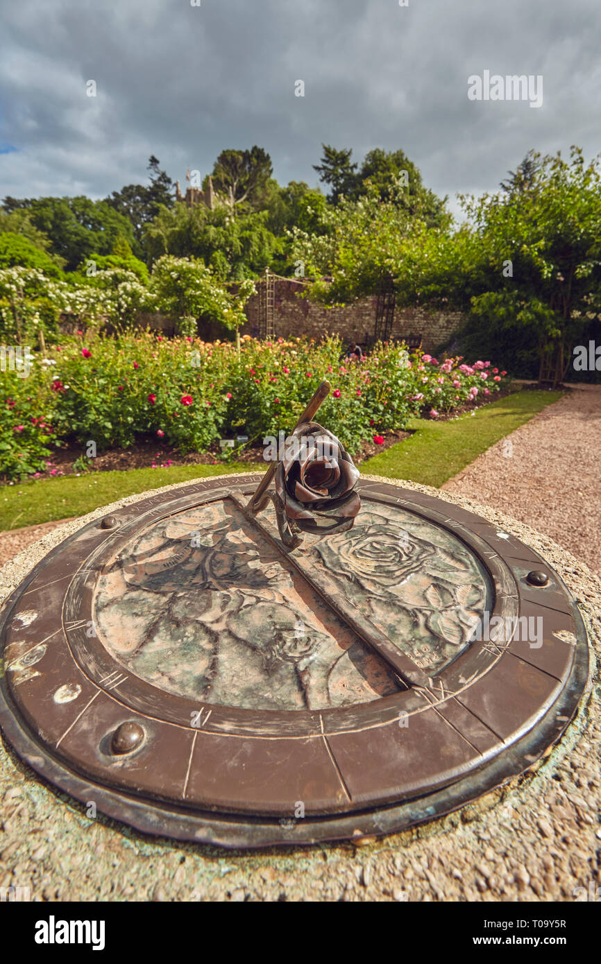 A sundial in a rose garden at the height of summer, Cockington, Torquay, Devon, Great Britain. Stock Photo