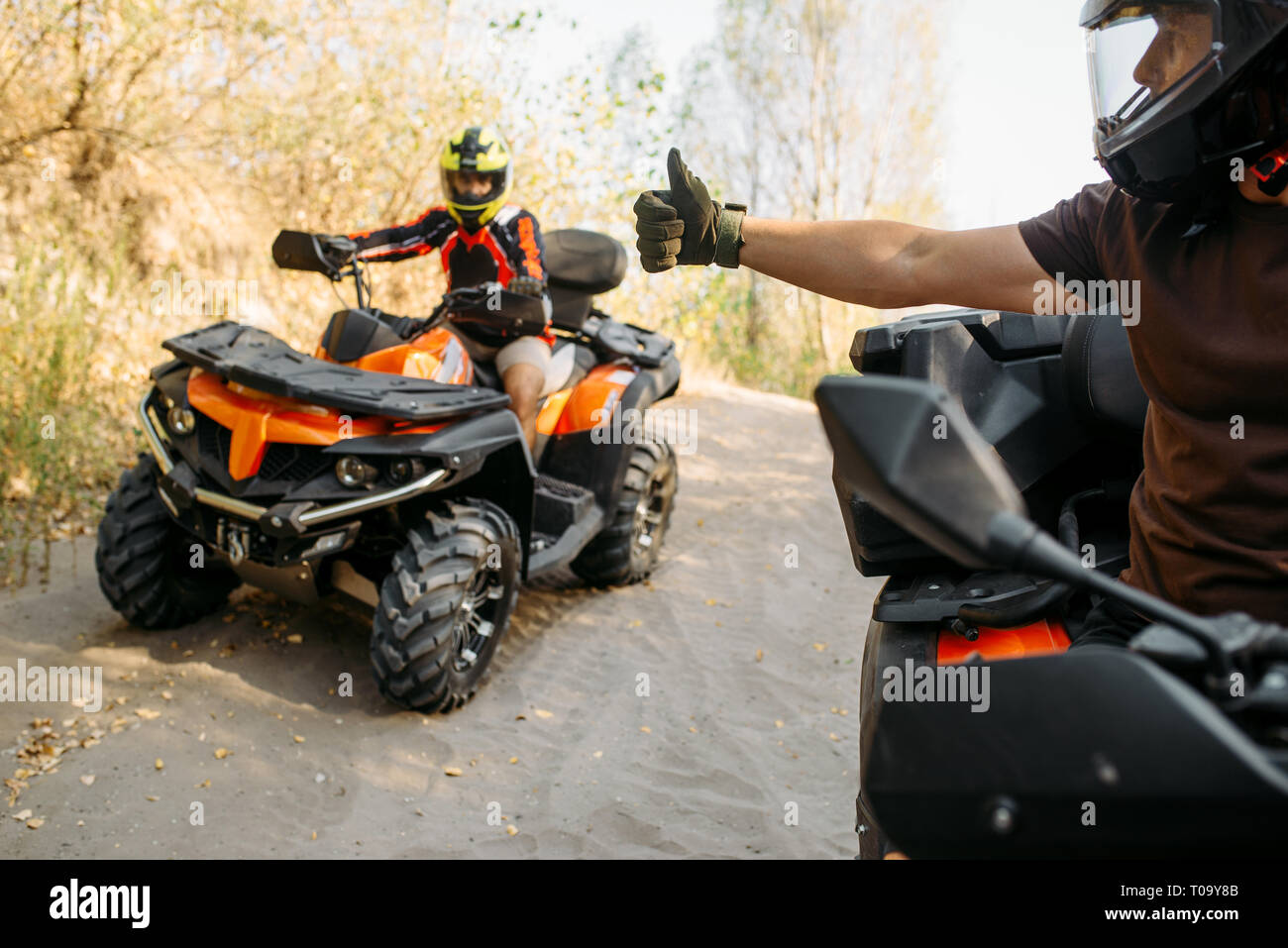 ATV rider in helmet showing thumbs up to his partner, offroad trip in ...
