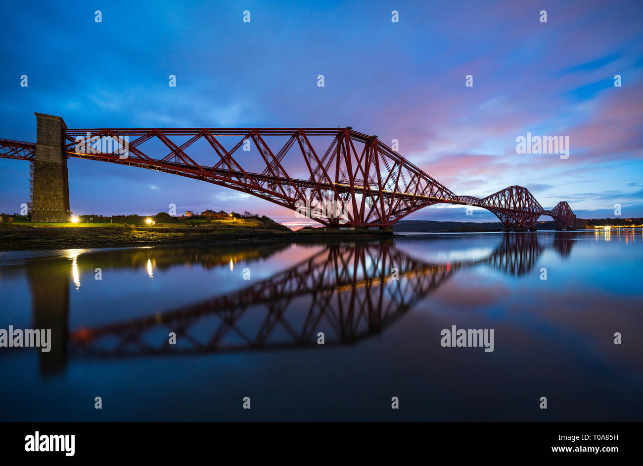 North Queensferry, Scotland, UK. 18th Mar, 2019. Soft pink light one hour before sunrise highlights the clouds above the Forth Bridge on a calm windless morning at North Queensferry in Fife, Scotland. Credit: Iain Masterton/Alamy Live News Stock Photo