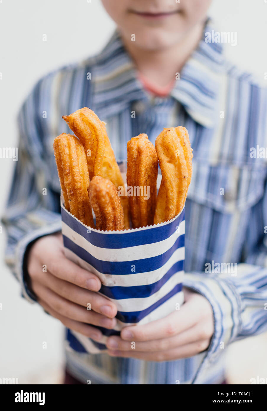 Boy holding paper bag with fresh churros Stock Photo Alamy