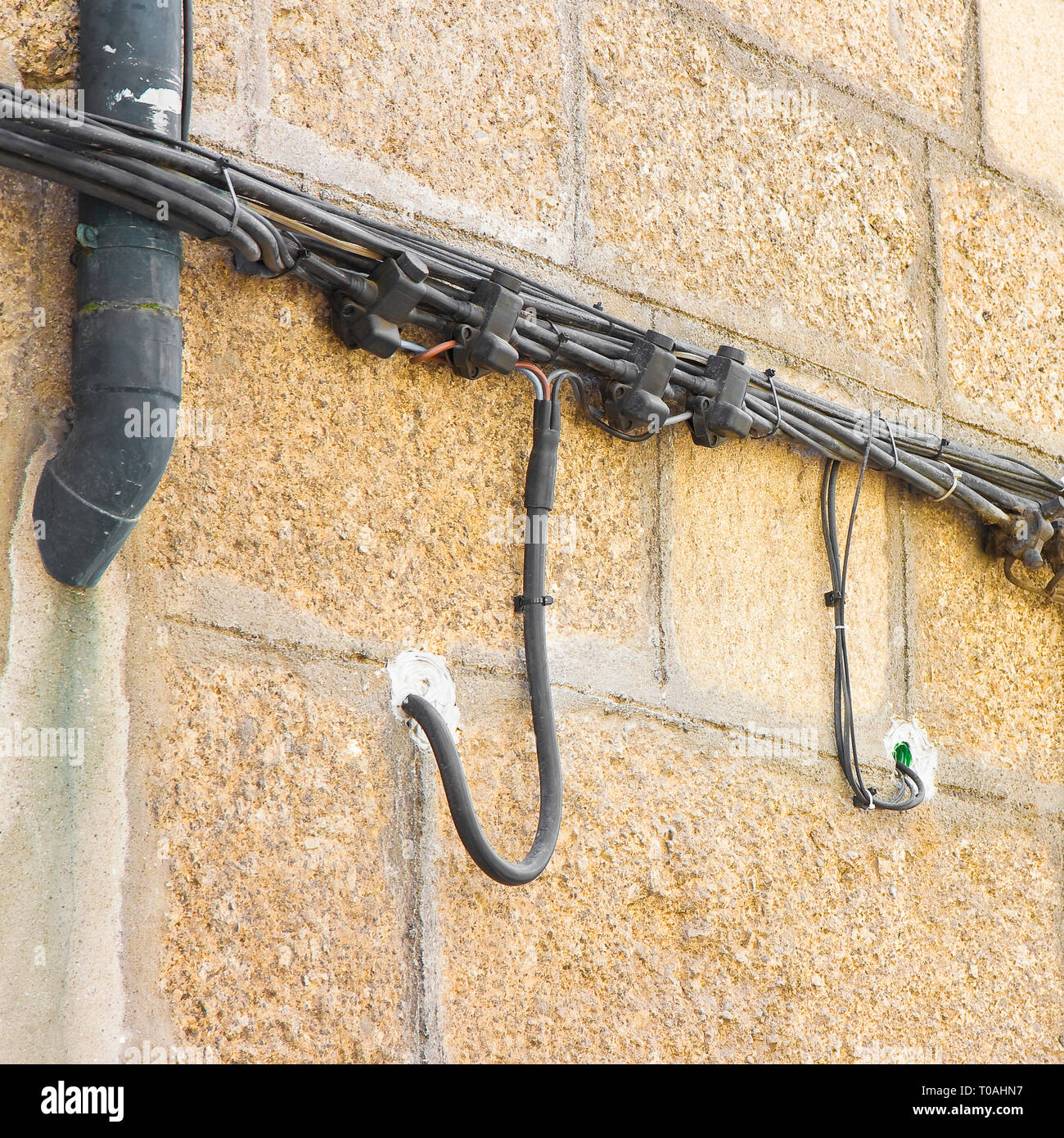 Electrical power cable against a stone wall Stock Photo Alamy