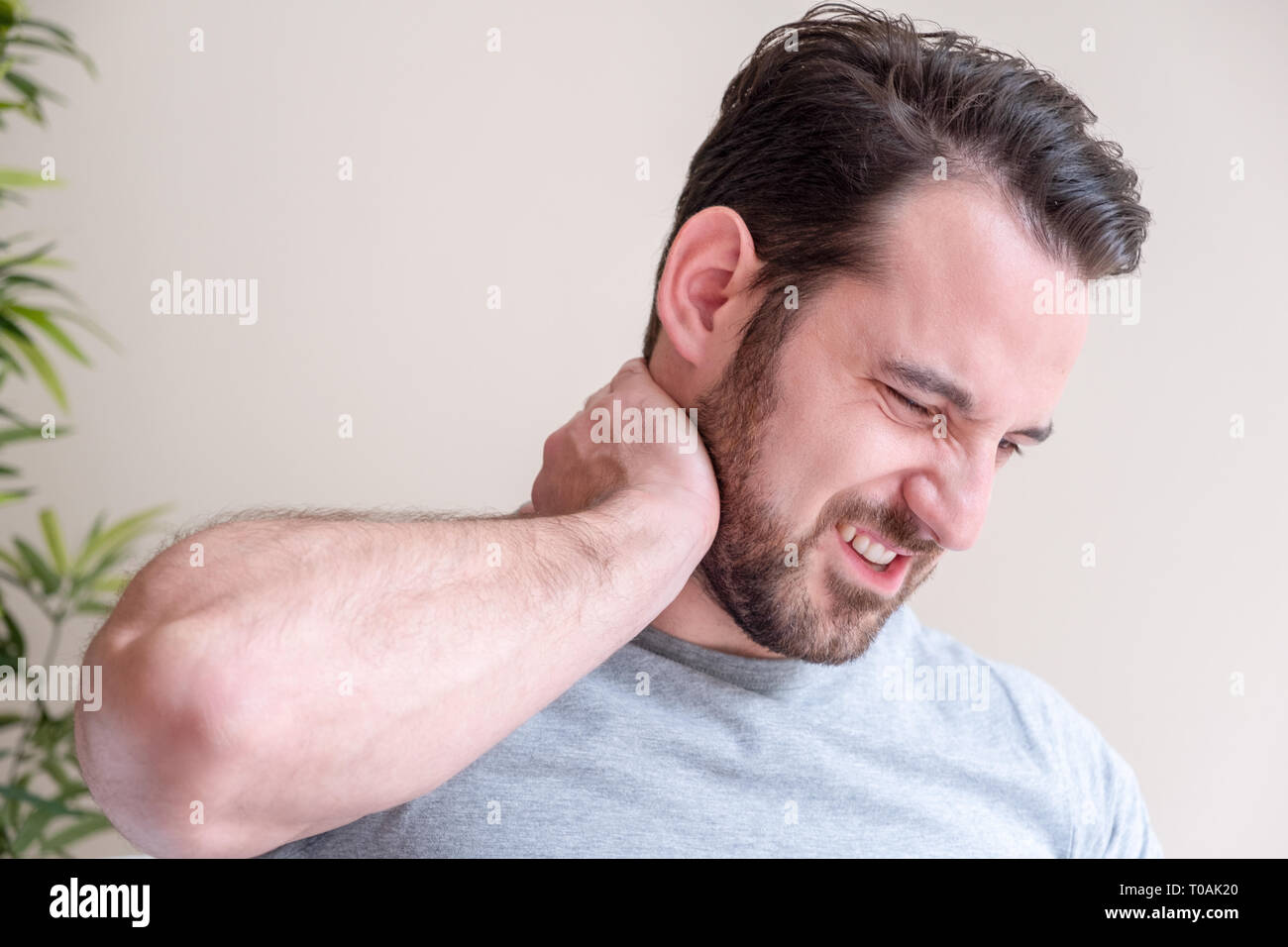 One man suffering neck pain seated on the sofa at home Stock Photo