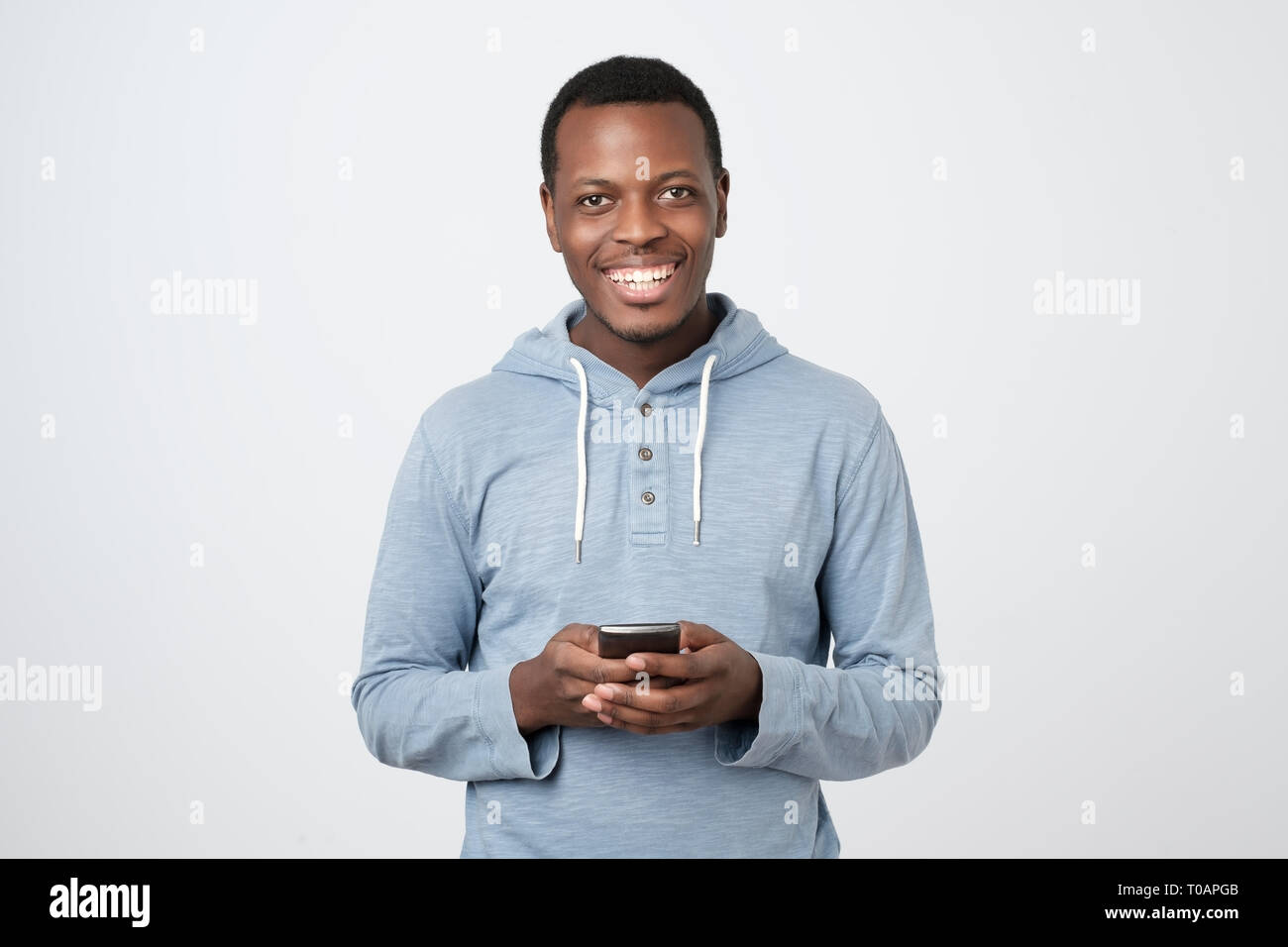 African young man using mobile phone chatting in internet with her friends. Stock Photo