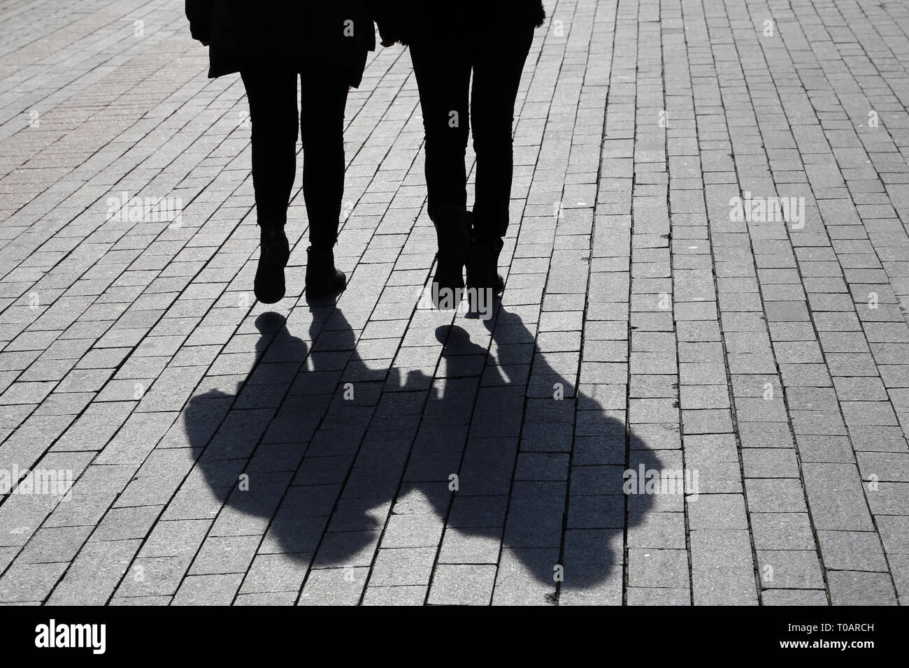 Silhouettes and shadows of two women walking down the street. Concept of female friendship, discussion, gossip, twins, dramatic life story Stock Photo