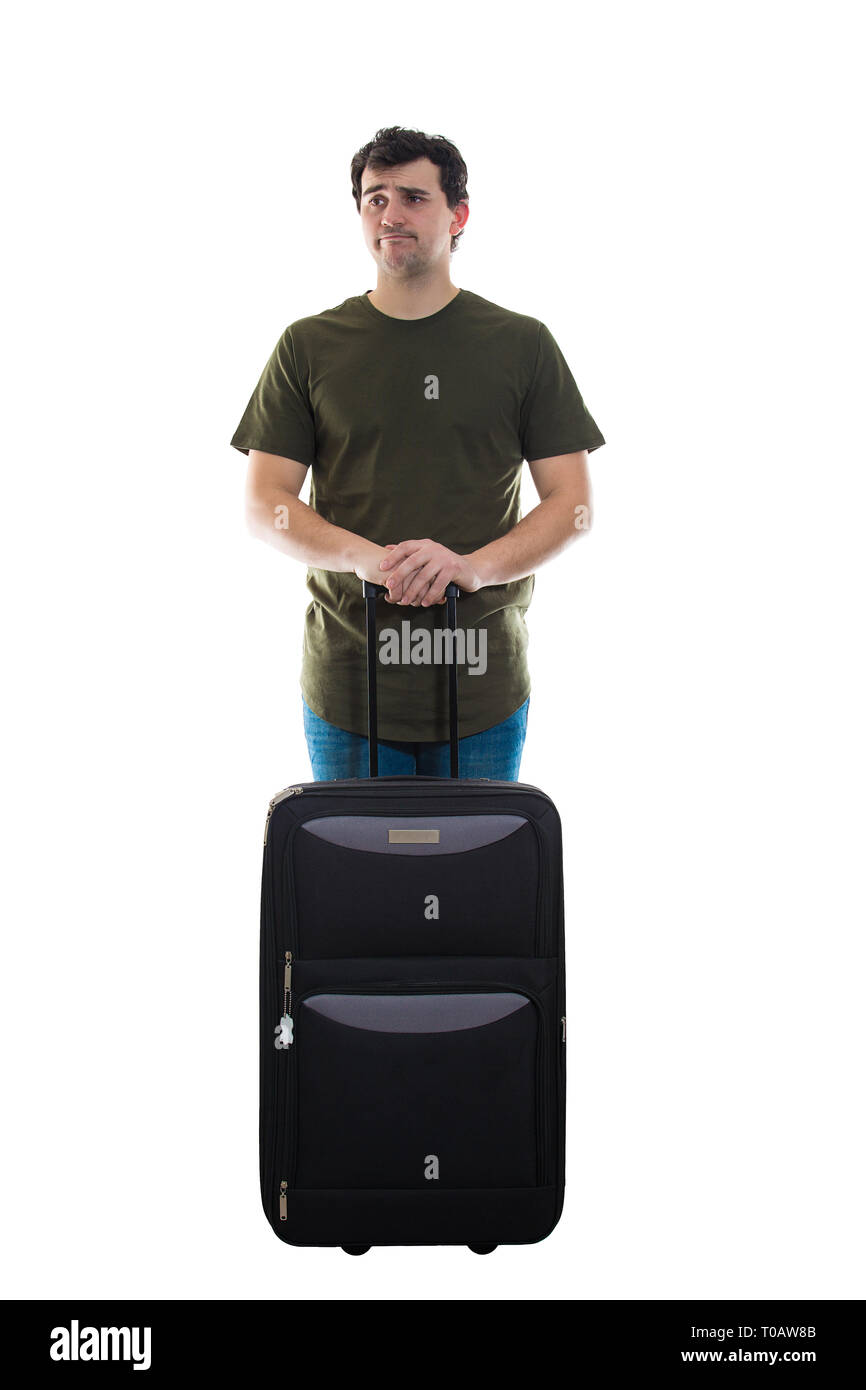 Perplexed man traveler standing behind his luggage isolated over white background looking away disappointed. Alone guy came late and has lost his tran Stock Photo