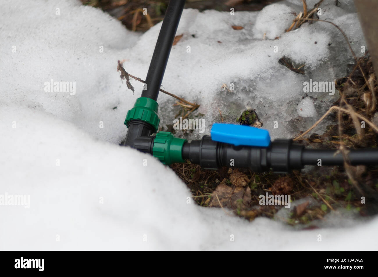 PVC water supply pipes above the melting snow, outdoor closeup, shallow depth of field Stock Photo