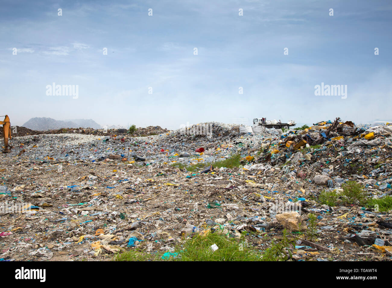 Open landfill area covered with plastic bottles, which ultimately going