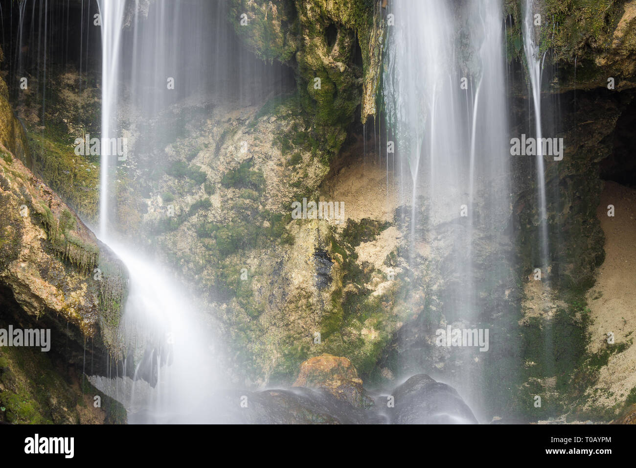 Close up, long exposure view of a sunlit waterfall with soft streams of ...