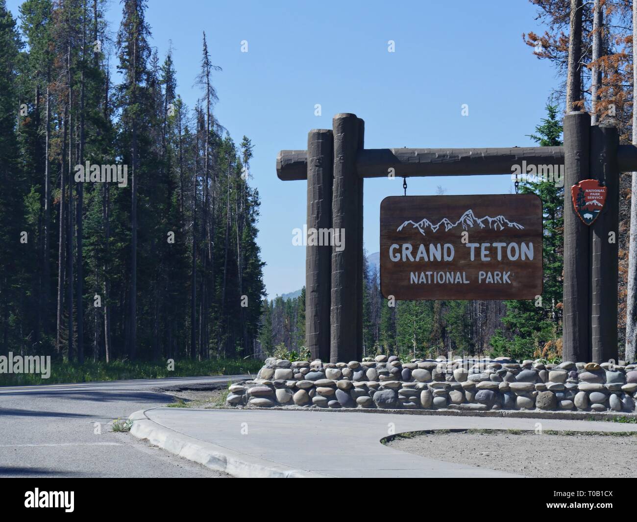 Grand Teton National Park sign with tall trees on the boundary of Yellowstone National Park. Stock Photo