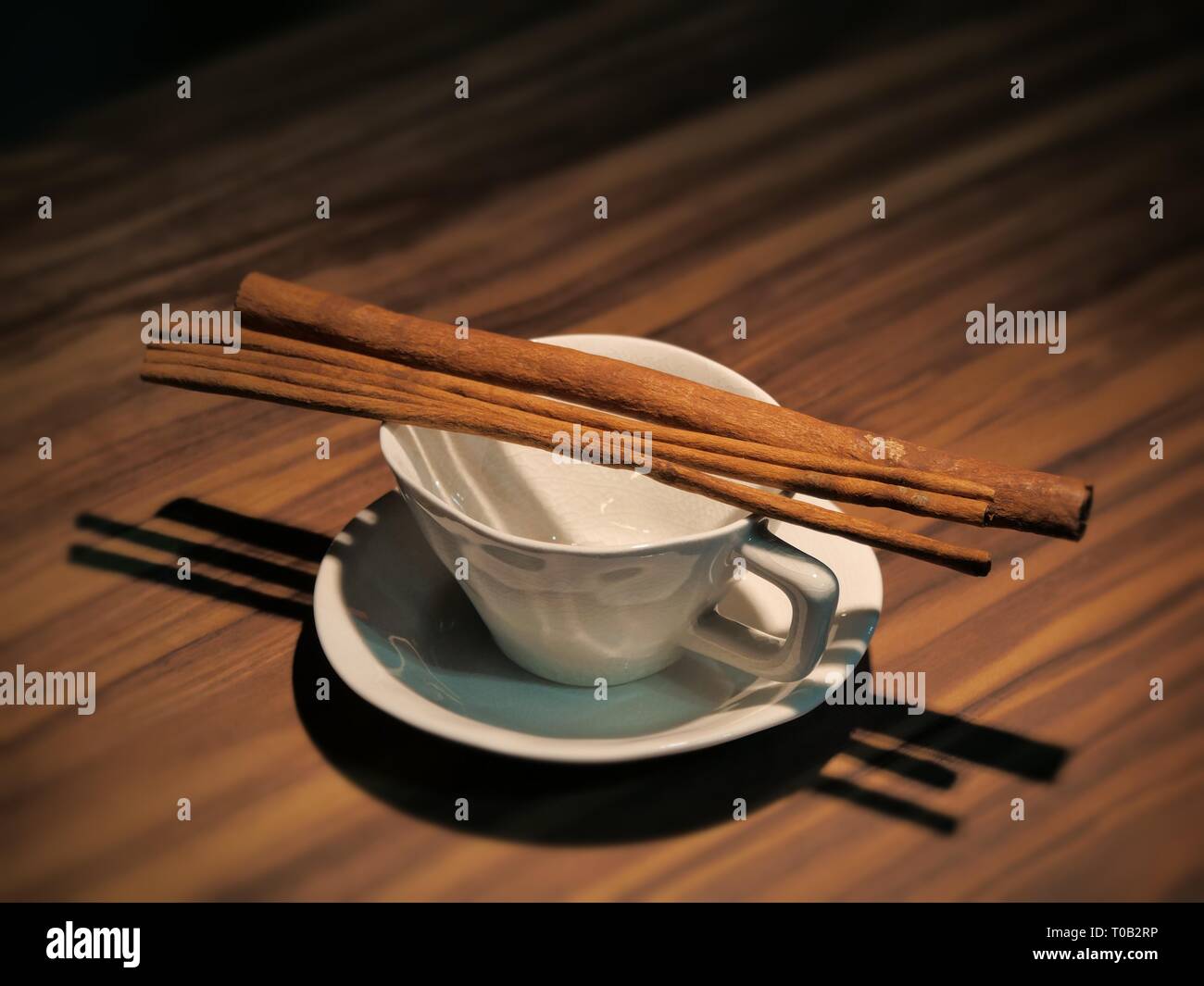 Empty coffee cup and cinnamon sticks on woodden table Stock Photo