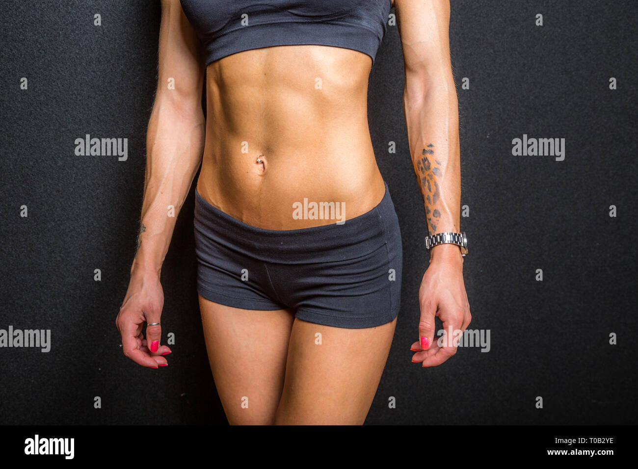 The abdominal muscles on a female fitness model. on black background. Stock Photo