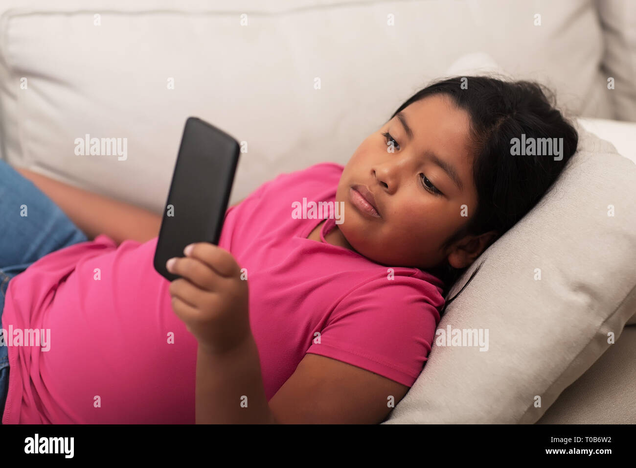 Elementary age student watching something on a mobile phone without parental supervision. Stock Photo