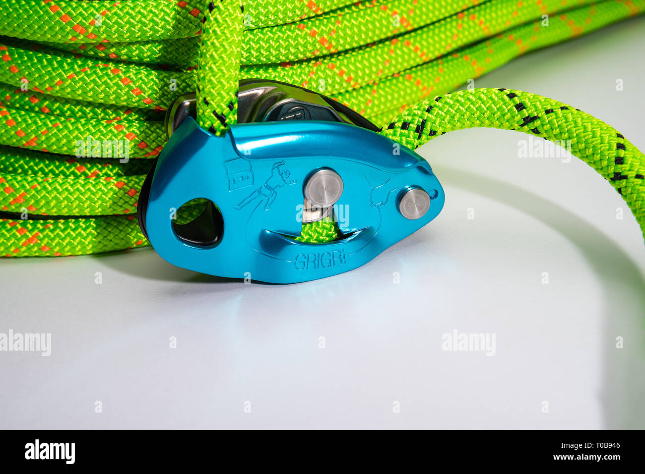 A professional, studio photo of a Petzl GriGri with a green Sterling rope fed through the ATC system on a white background. Stock Photo