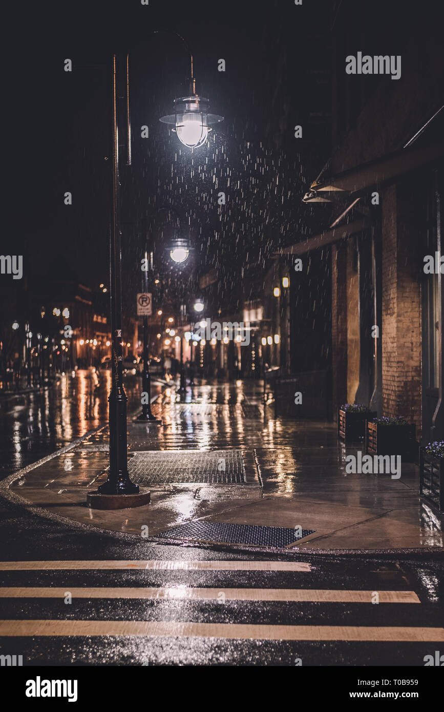 Light from a street lamp catches rain drops as they fall in downtown