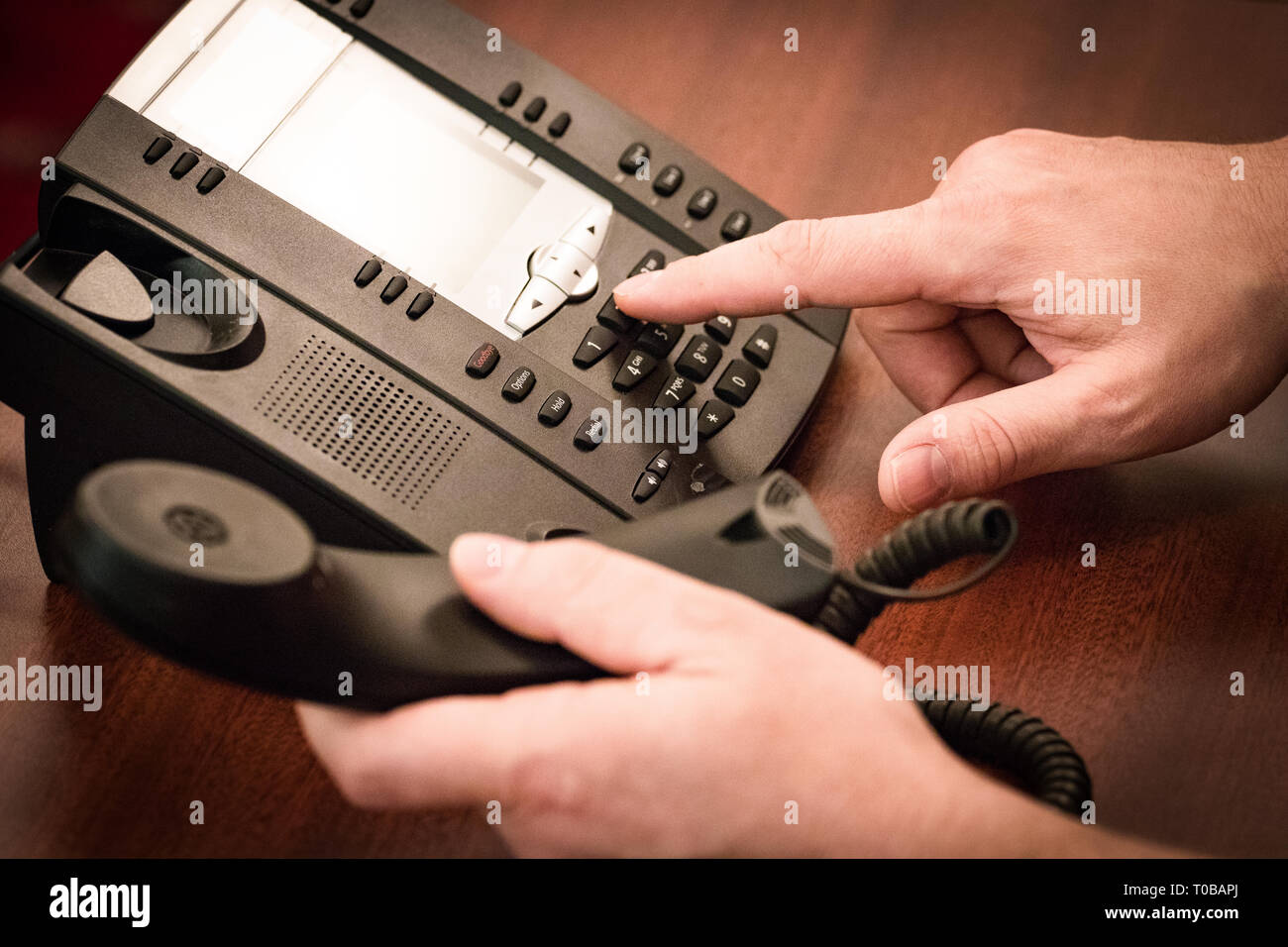 Finger dialing phone call on touch tone telephone. Stock Photo