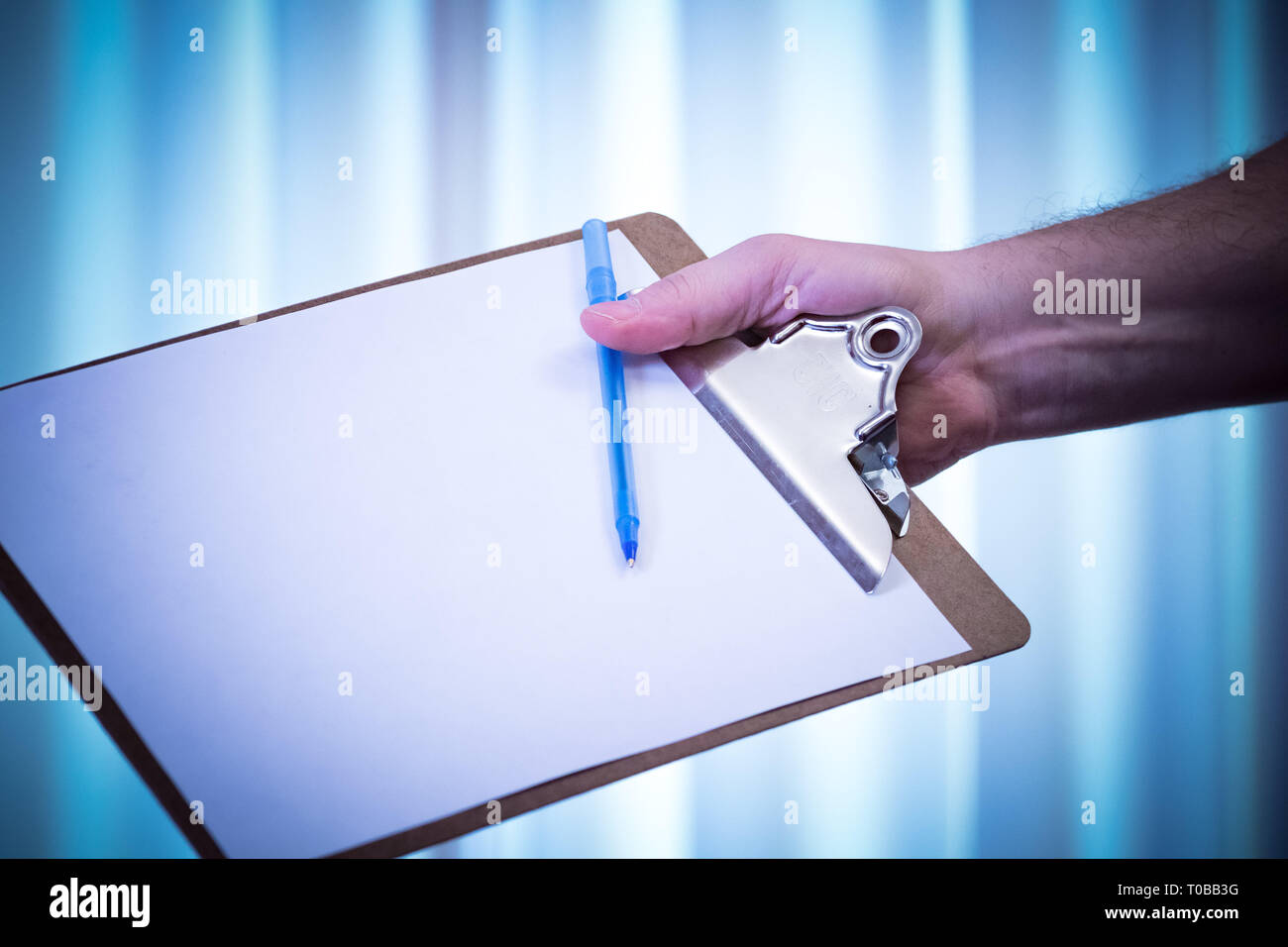 Handing out clipboard and pen to sign up names/signatures and fill out; blank paper, blue tone Stock Photo