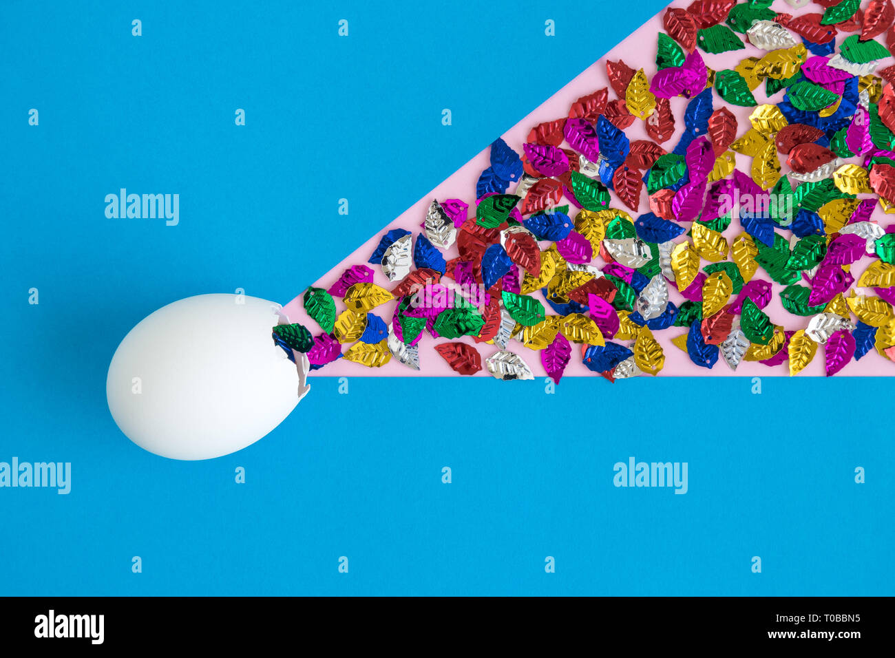 Egg shell with colorful leaves on blue background minimal easter and spring creative concept. Stock Photo