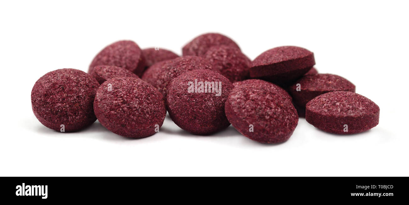 Black chokeberry fruit pills, large detailed isolated tablets macro closeup, organic raw aronia melanocarpa berry fruits pill pile, burgundy colored Stock Photo