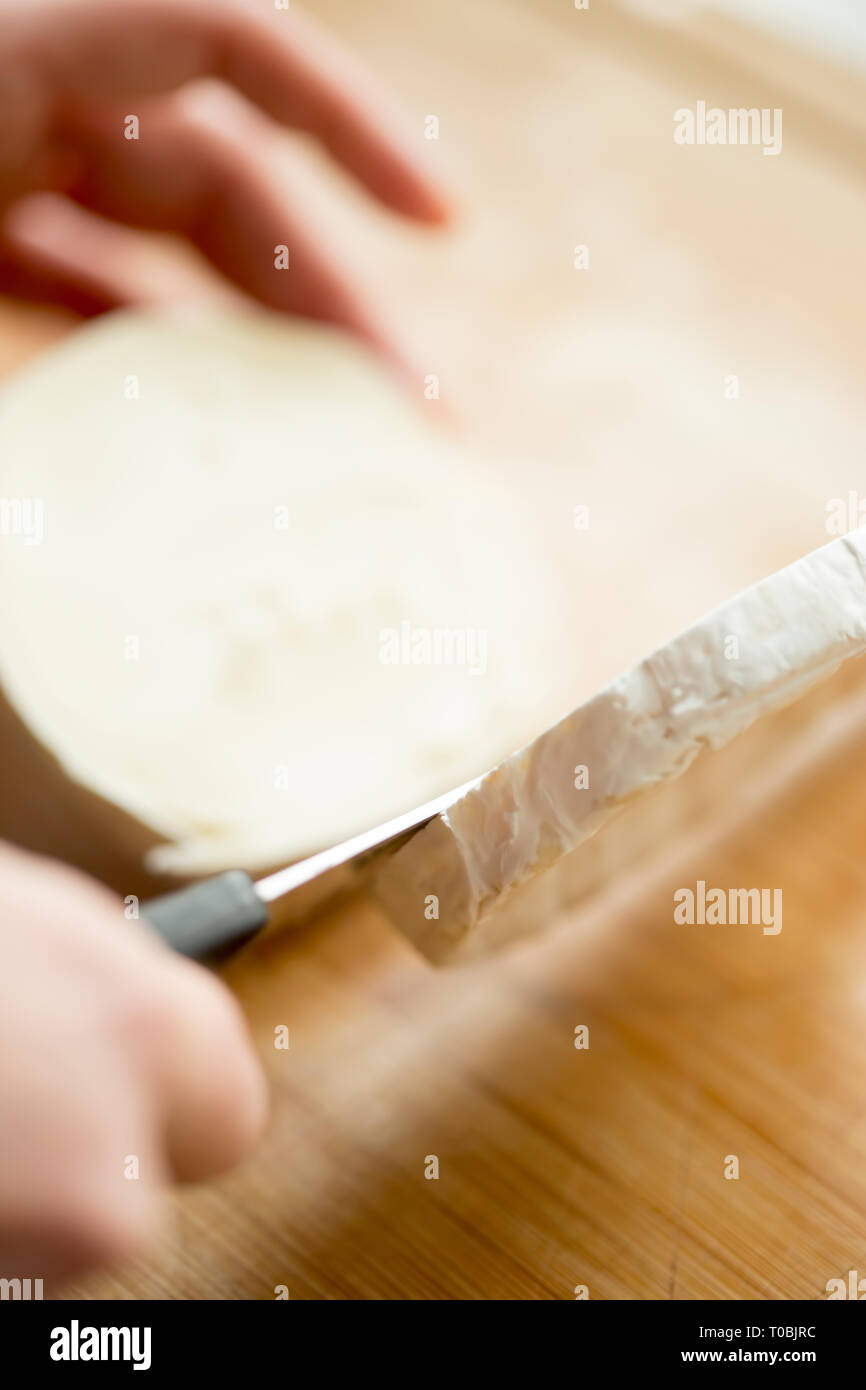Cutting Brie cheese with knife Stock Photo Alamy