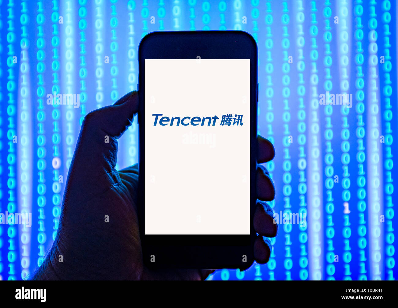 Person holding smart phone with Tencent  logo displayed on the screen. Tencent is a Chinese multinational investment holding conglomerate Stock Photo