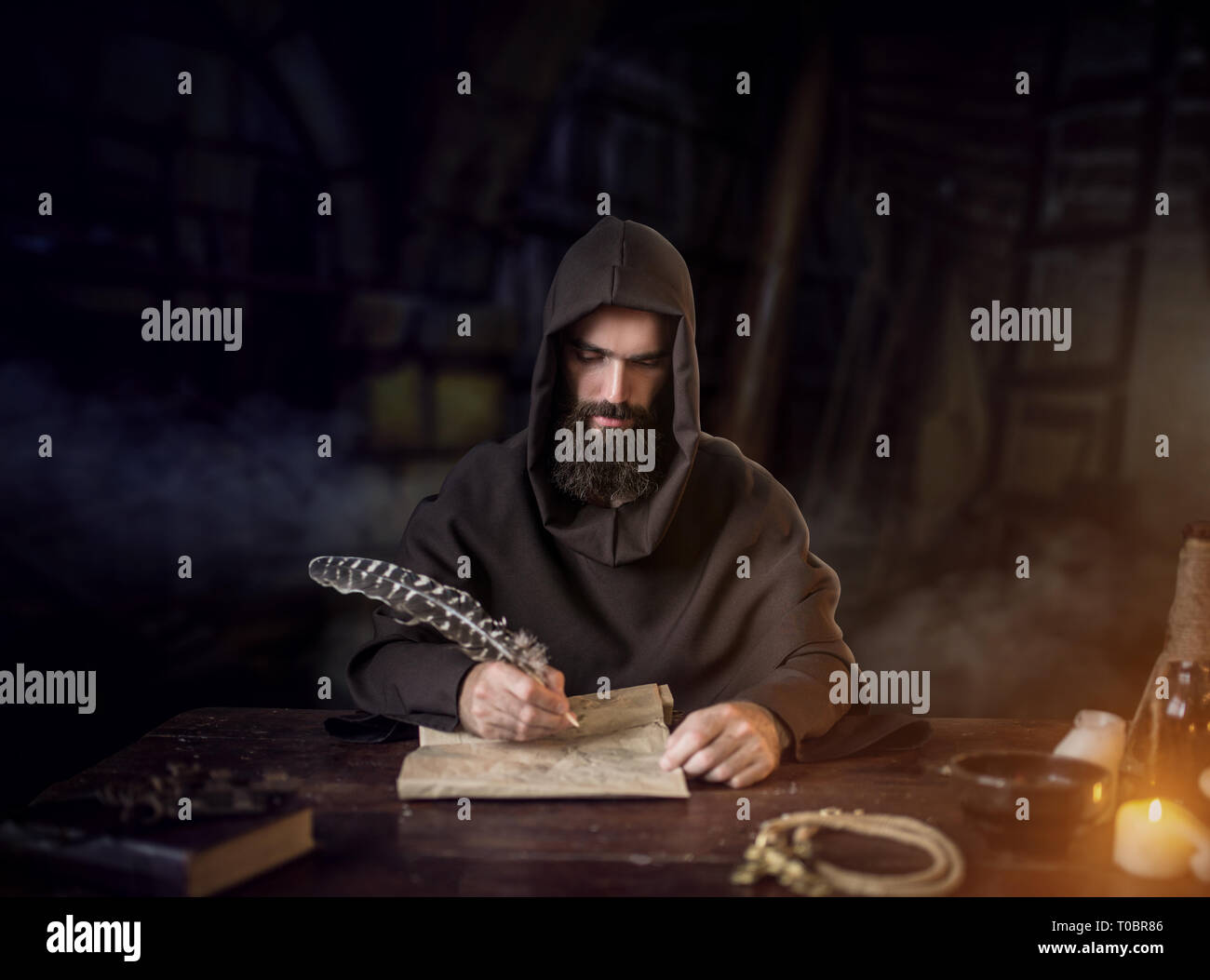 Medieval monk in robe and hood writes with a goose feather, black ...