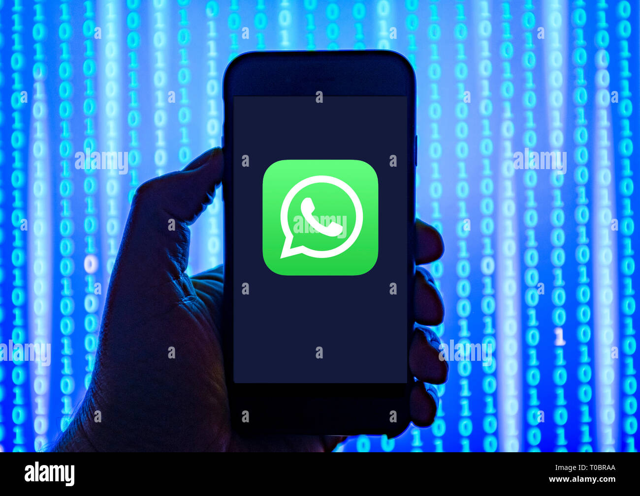 Person holding smart phone with  WhatsApp  logo displayed on the screen. Stock Photo