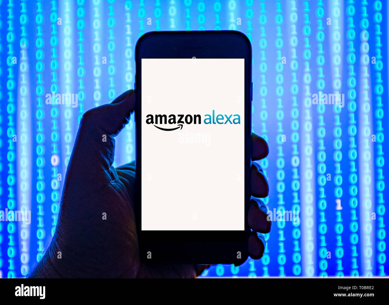 Person holding smart phone with Amazon Alexa virtual assistant  logo displayed on the screen. Stock Photo