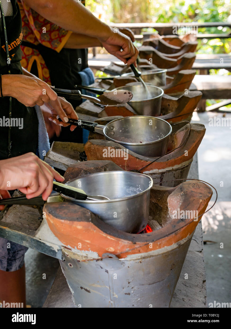 Tourists in SE Asian Lao cooking lesson making purple sticky rice on clay stoves, Tamarind cookery school, Luang Prabang, Laos Stock Photo