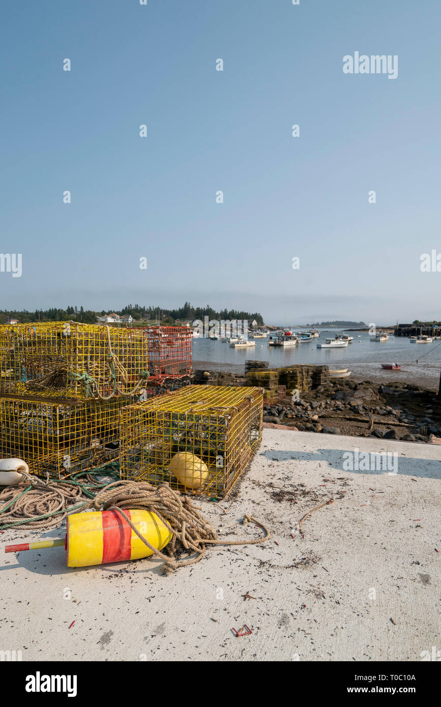 Lobster traps sitting at the shoreline the harbor is at low tide in the background Stock Photo