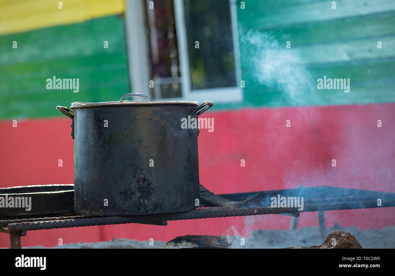 Old dark cooking pot on a wooden fireplace with smoke background Stock