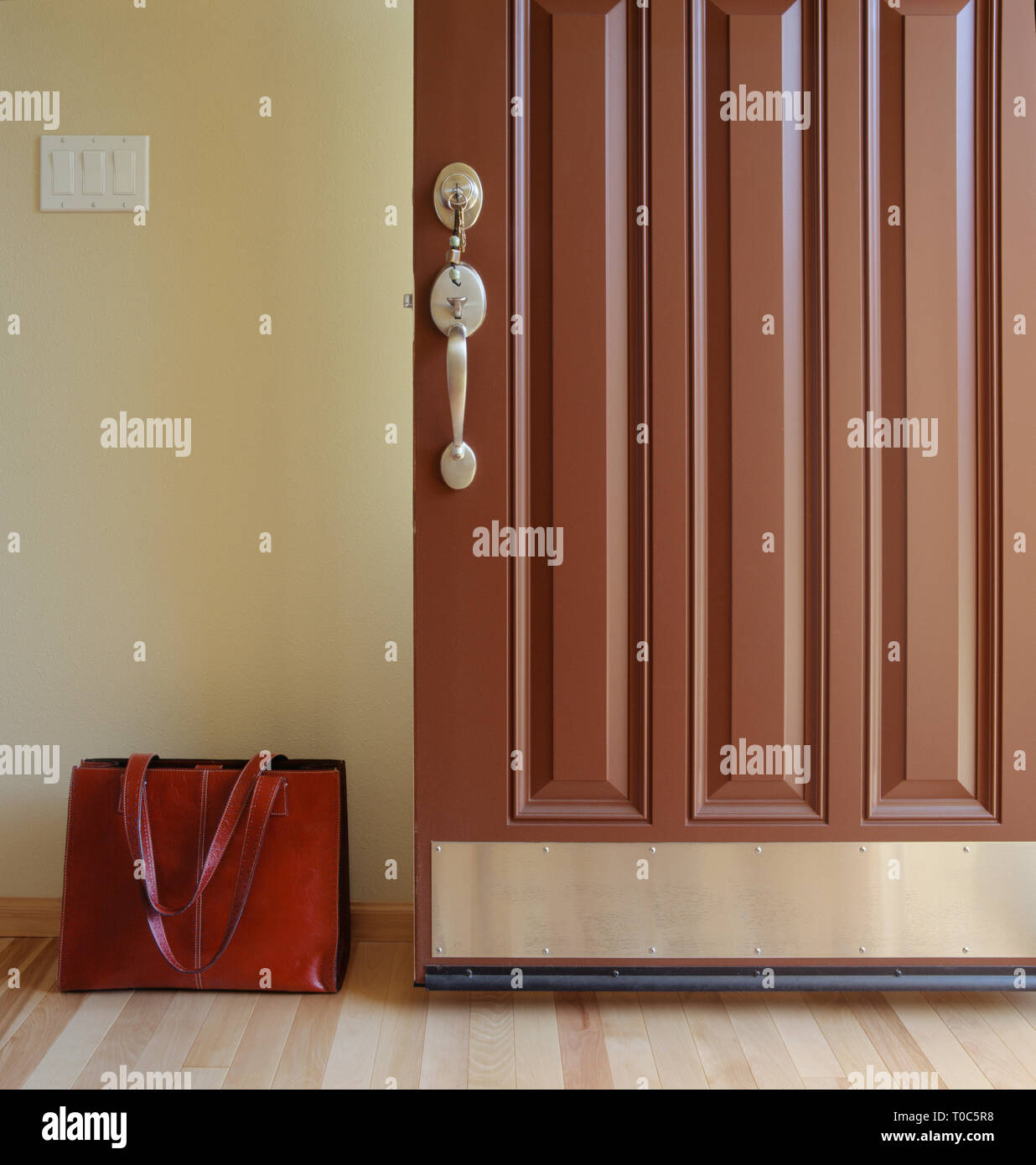 Open front door of house with keys in lock and briefcase brief bag in