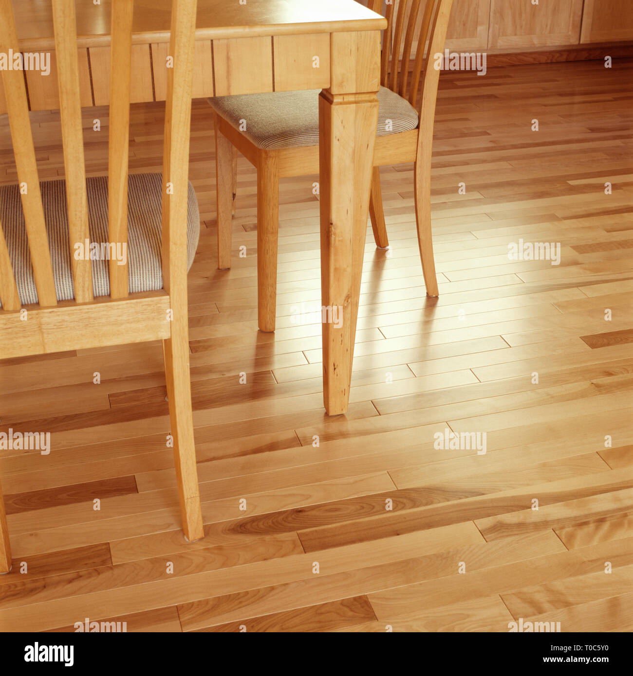Clean, shiny, maple wood hardwood floor flooring in contemporary upscale home kitchen dining room interior Stock Photo