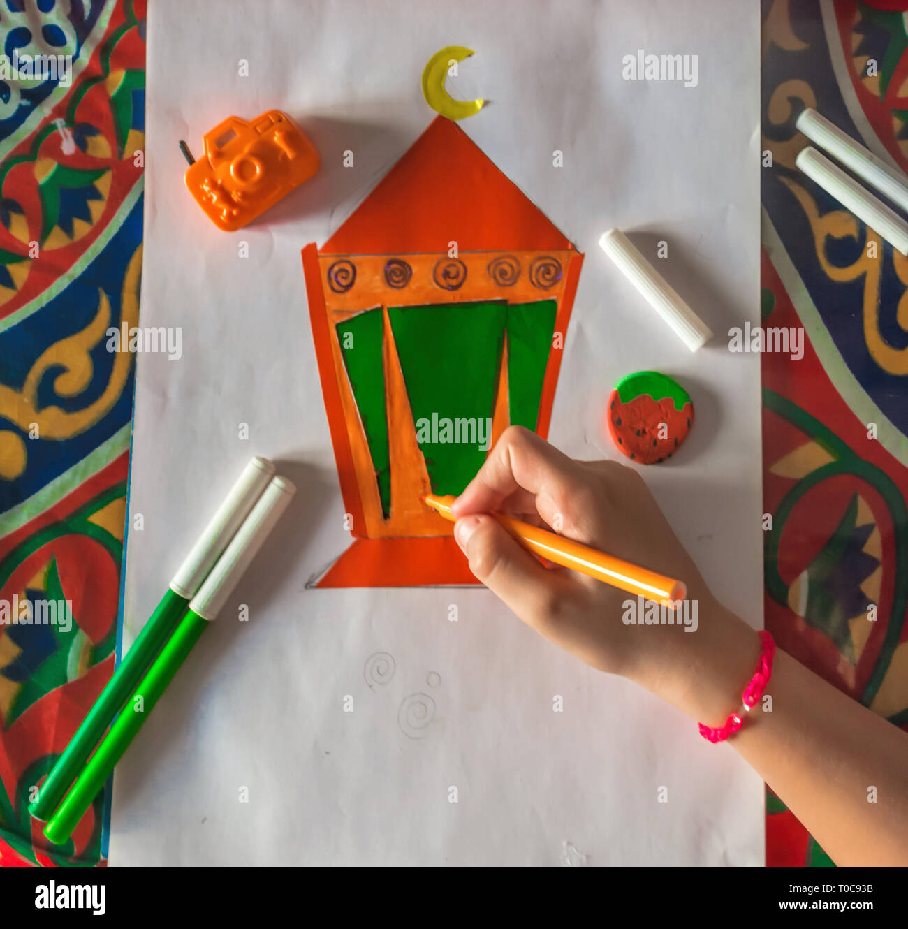 Young Muslim kid hand drawing Ramadan lantern on white paper Stock Photo