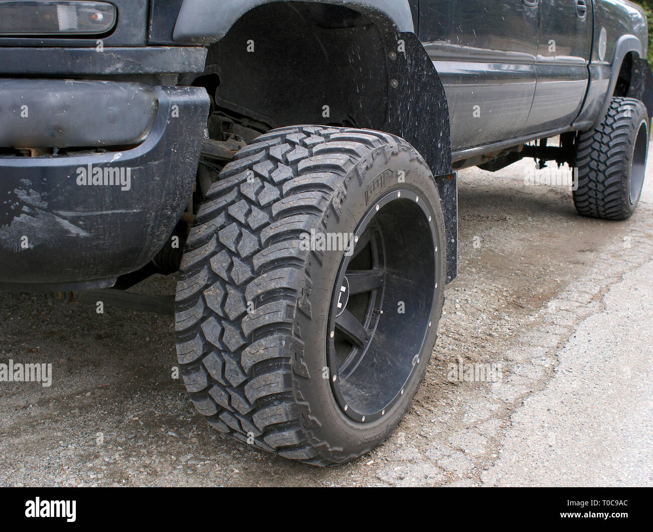 Low angle of black four wheel drive pickup truck showing the rugged front tire tread and wheel. Stock Photo