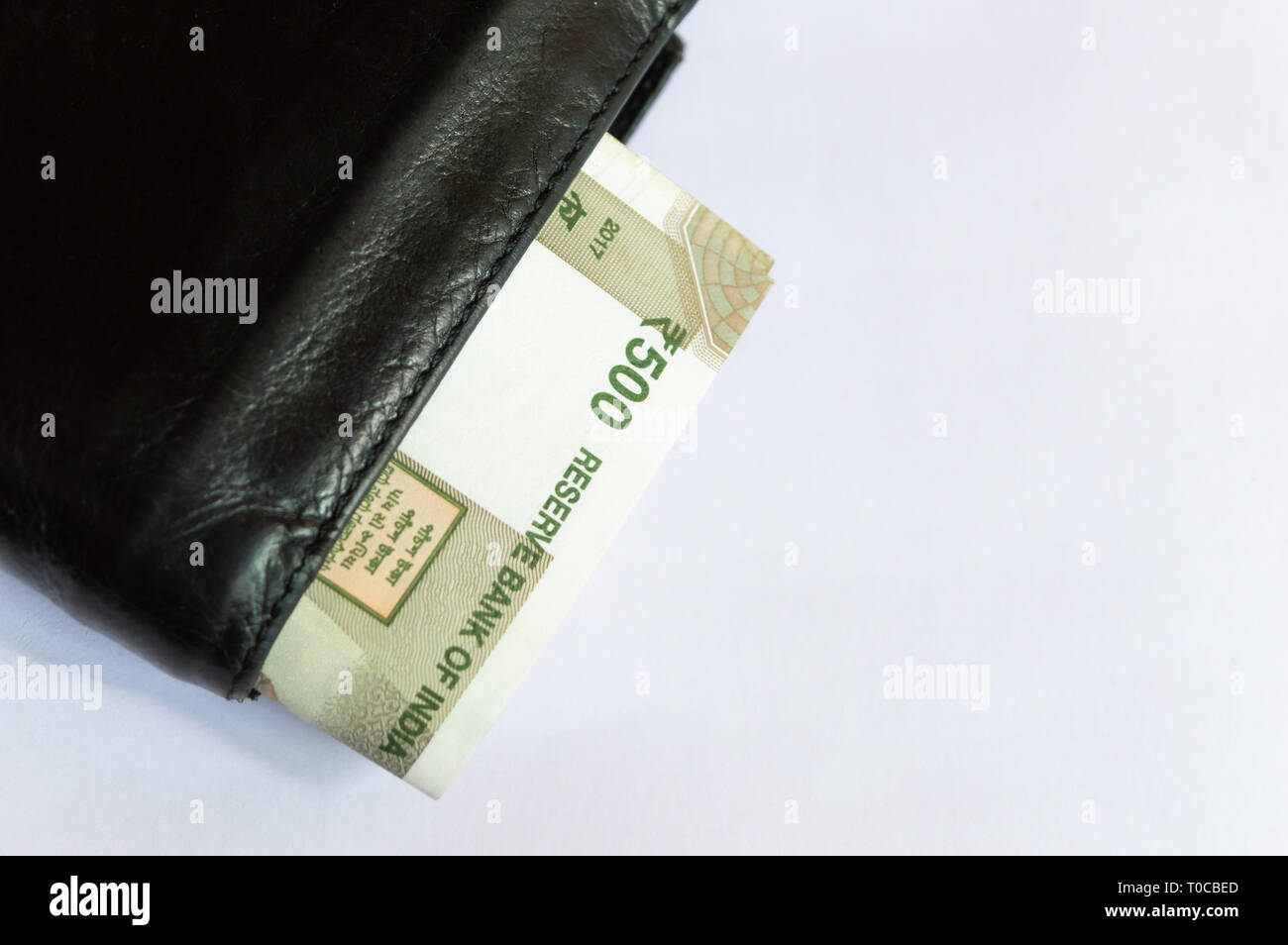 indian currency notes rs 500 in a black leather wallet on a white background top view T0CBED