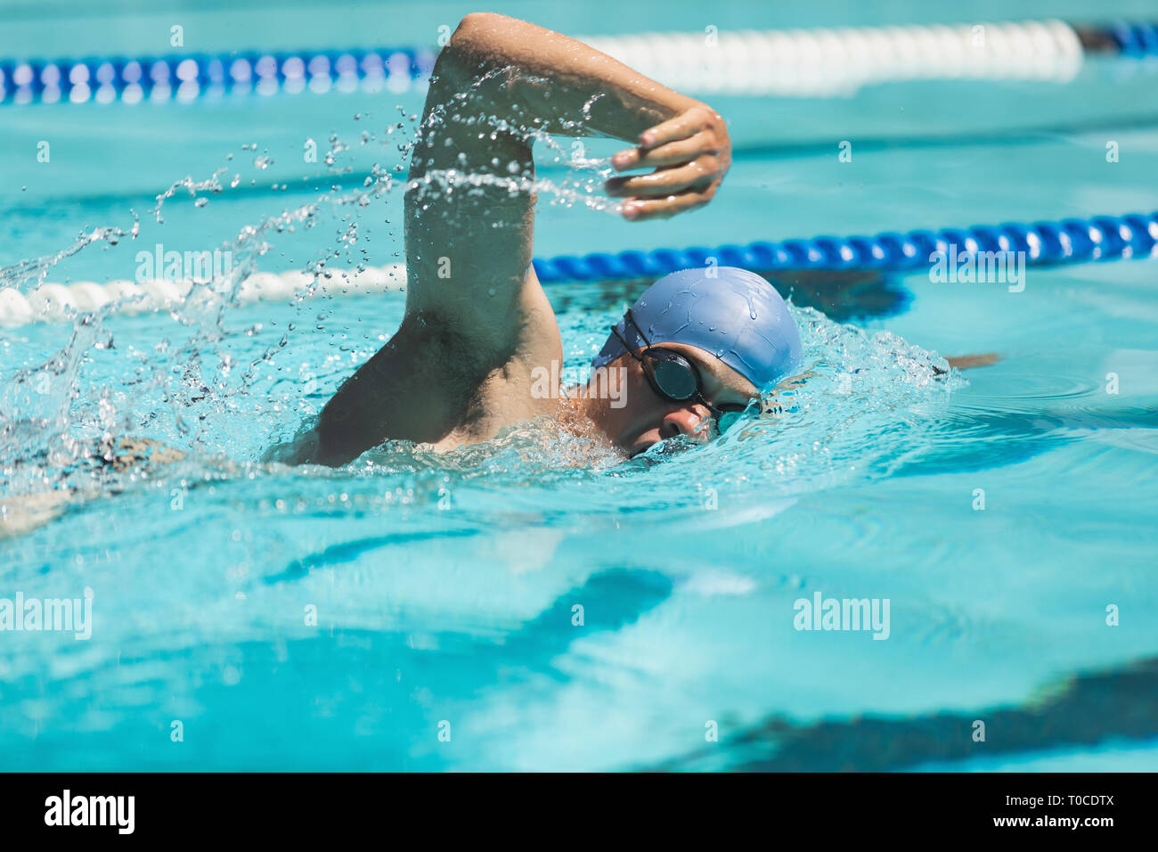 Young Caucasian male swimmer swimming freestyle in swimming pool Stock