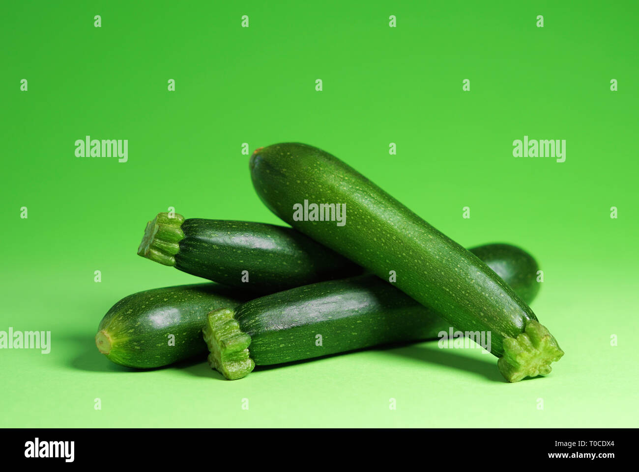 Zucchini vegetables portrait concept with four fresh organic baby zucchini close up view on green background with copy space. Stock Photo